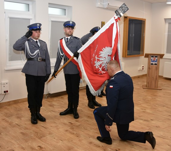 Na zdjęciu policjanci w umundurowaniu służbowym wyjściowym. Komendant całuje sztandar Komendy.